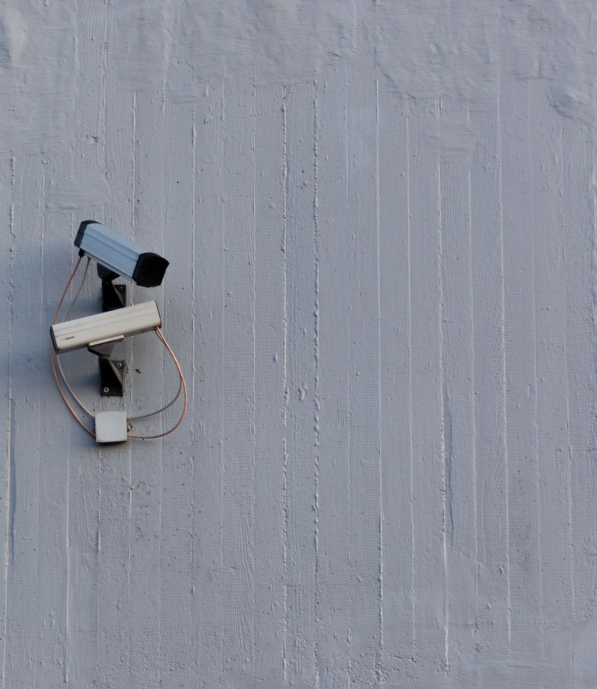 Security cameras mounted on a building wall, representing external monitoring of AI agents