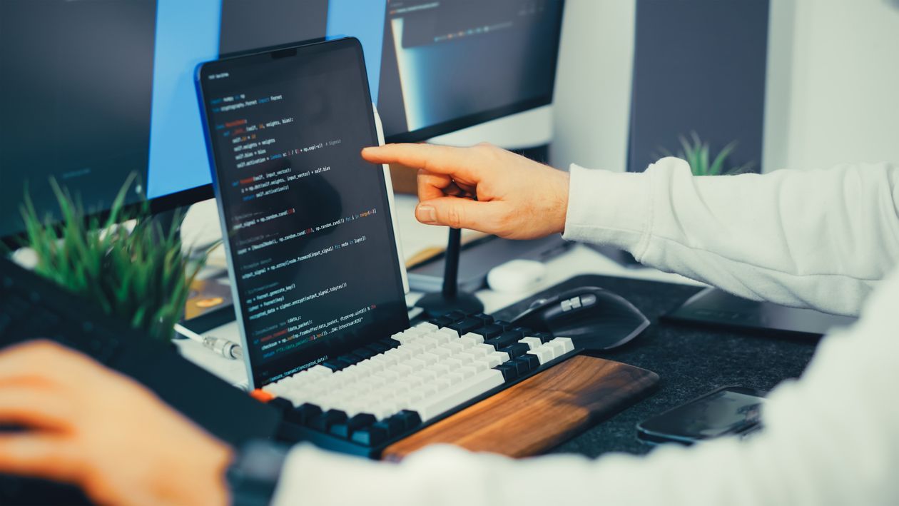 A programmer typing code on a laptop, representing the AI coding agent running on the developer's machine