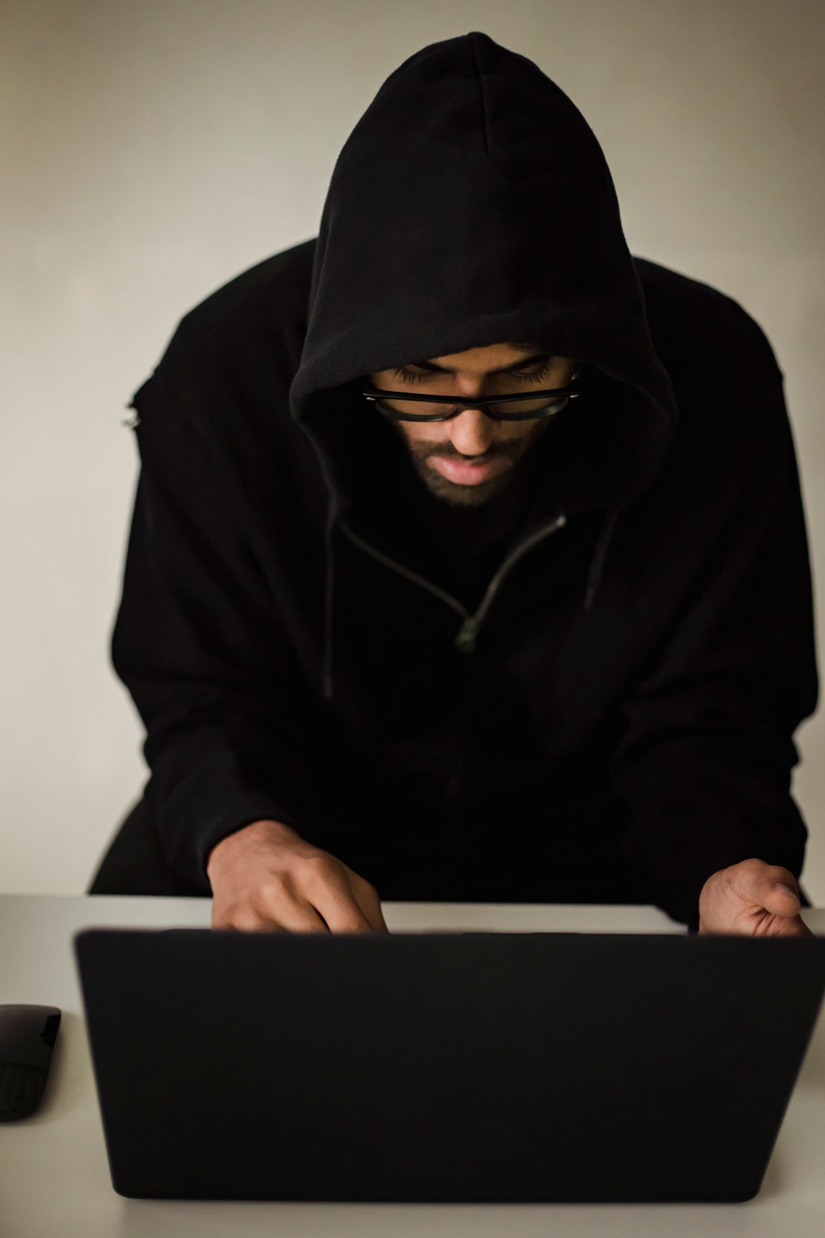 Person working at a laptop in a dimly lit room, representing the kind of environment where credential exposure happens