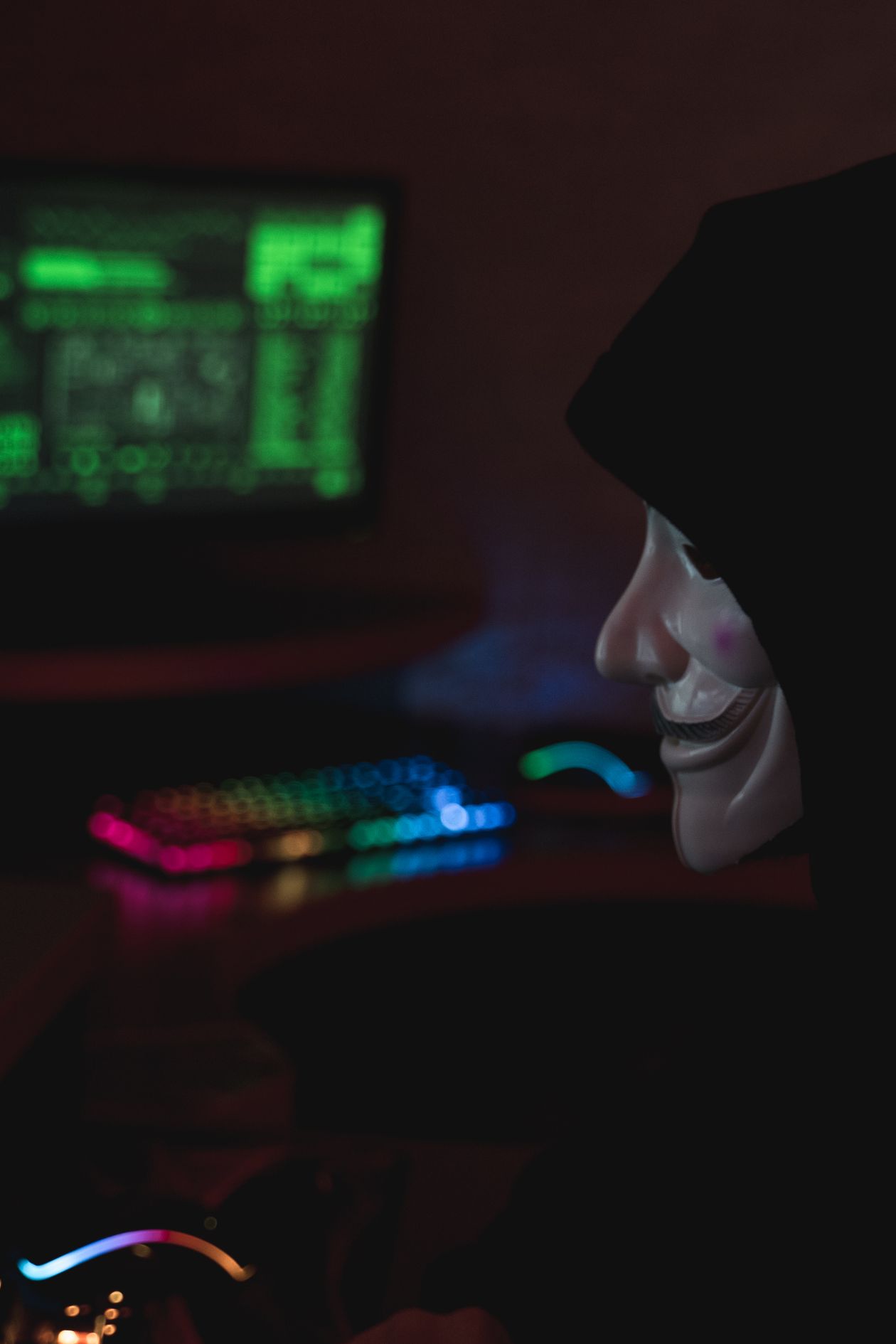 A hooded figure at a computer, symbolizing cybersecurity threats from prompt injection