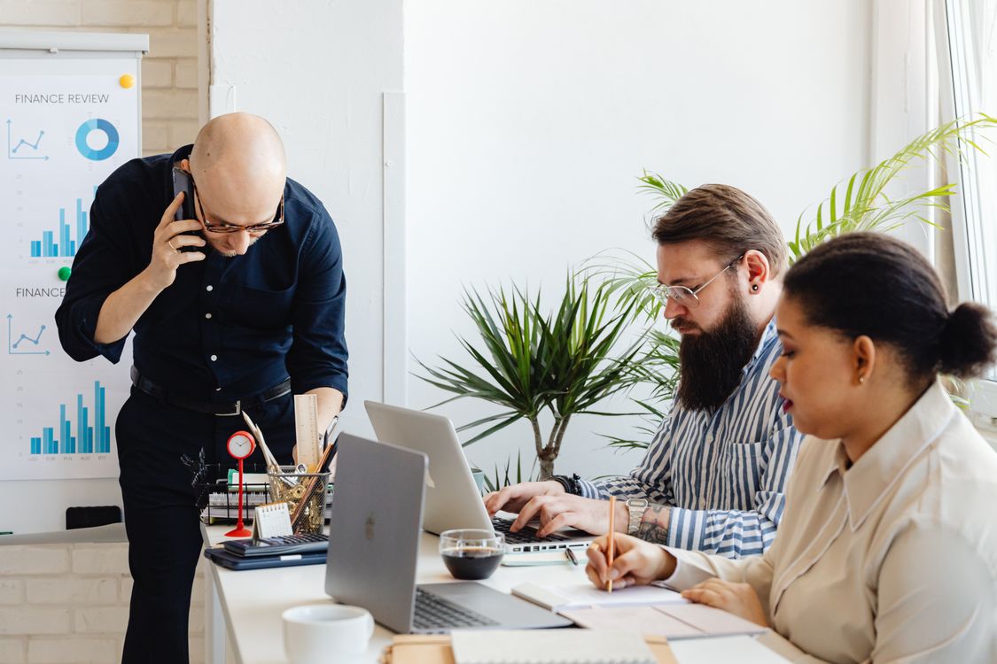 Team collaborating around a laptop in a modern office, representing agents working inside everyday business workflows