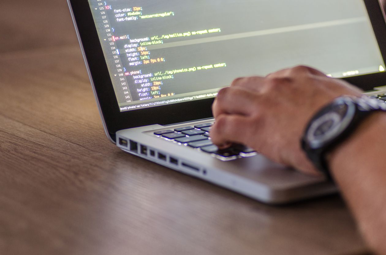 A developer reviewing code on a laptop — the Migration Report flags the workflows, but a human still does the fixing
