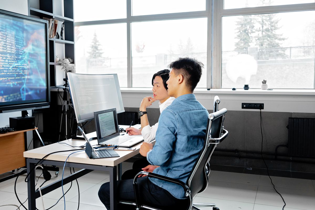 Two developers reviewing code together on a large screen — the human pairing session that Ruflo's swarm model automates