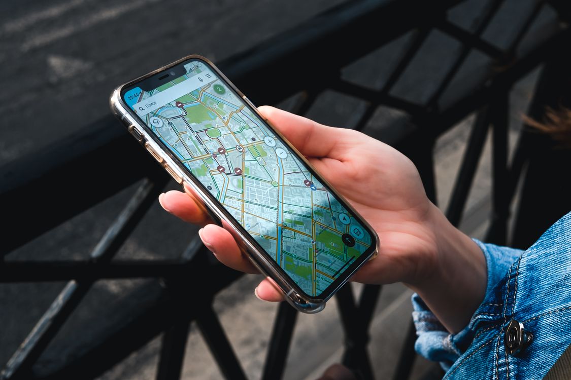 A hand holding a smartphone with a map navigation app open — the Amap data the agents repeatedly scraped